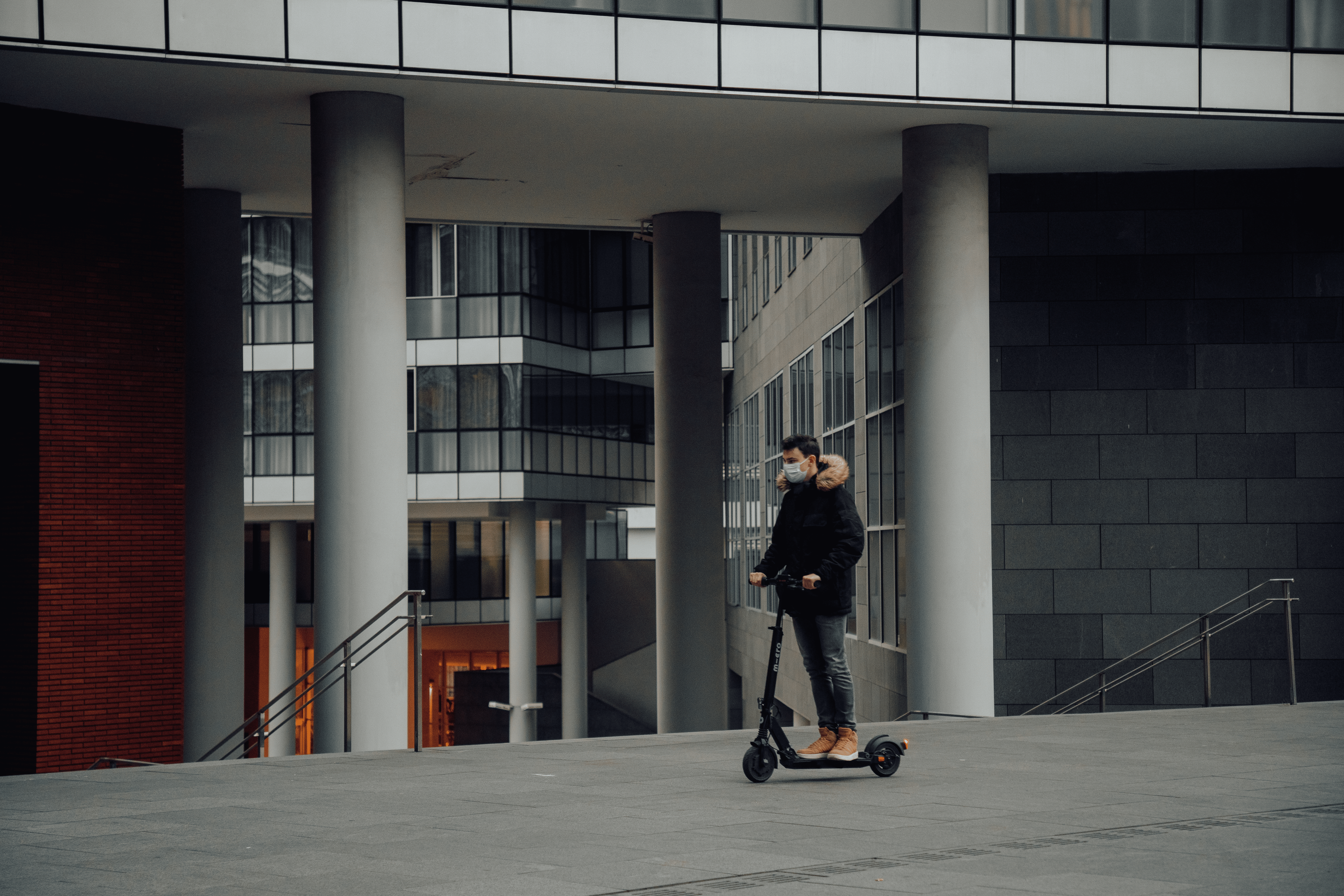 Adopter la trottinette pour réduire son budget transport Image homme à trottinette en extérieur avec un masque