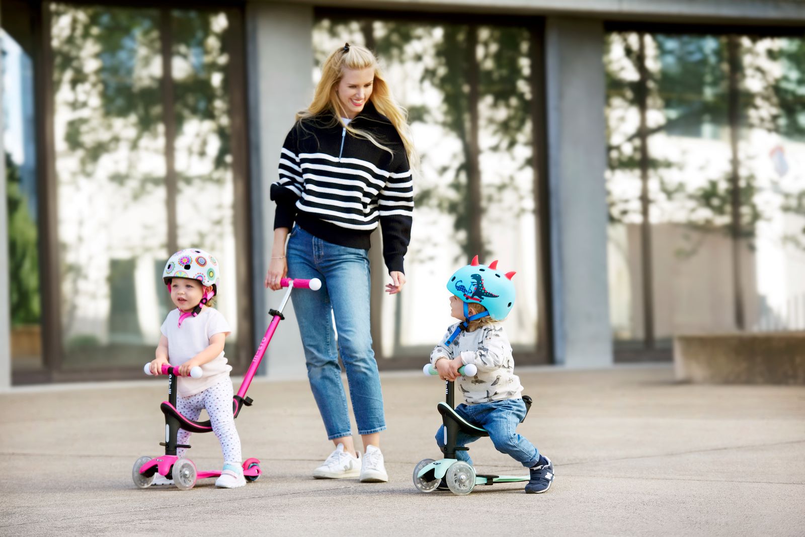 deux petits enfants sur leur trottinette avec siège bébé roulant avec leur maman